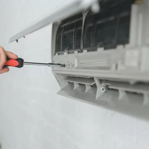 partial view of male worker repairing air conditioner with screwdriver